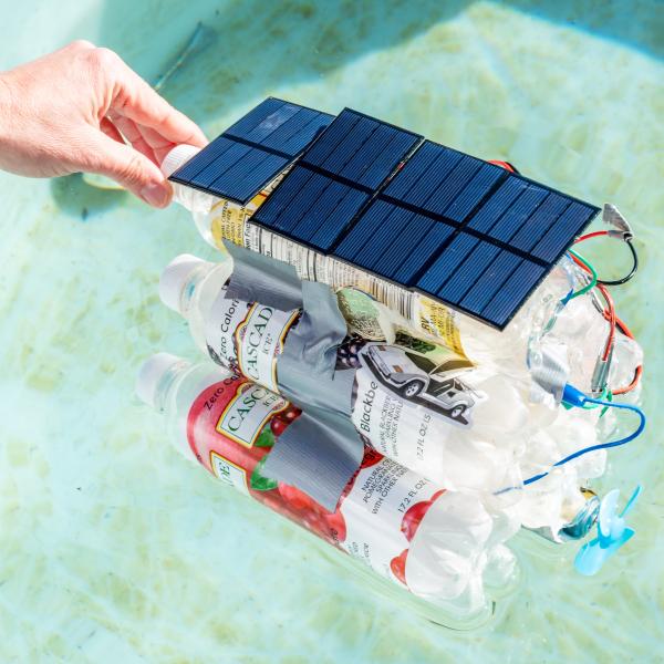 A boat made of plastic bottles and solar panels floats on water.